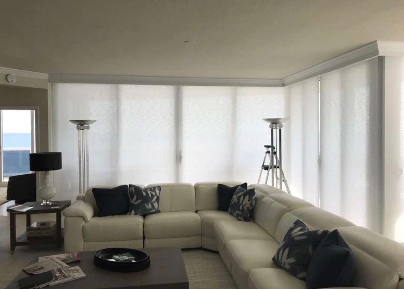Modern white kitchen featuring custom cellular shades on large windows, marble countertops, natural light, and energy-efficient window treatments for contemporary homes.
